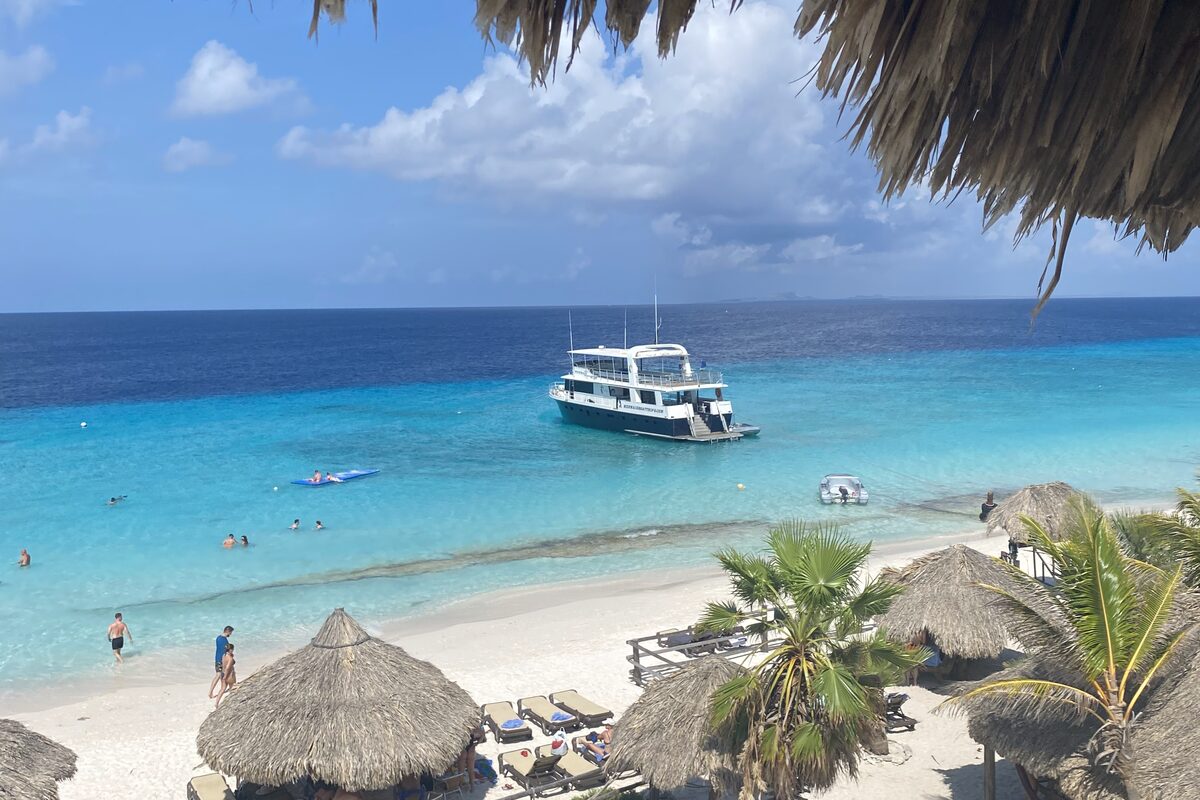 Strand met palapa's en boot op Curaçao