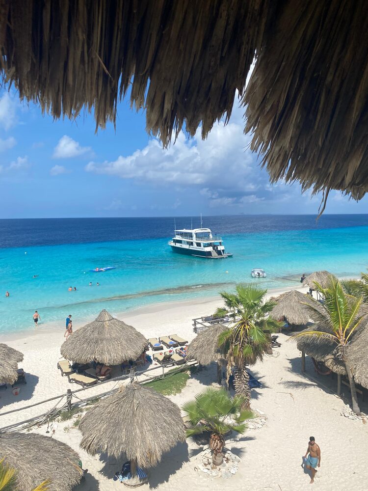 Wit strand met palapa's en een boot op Klein Curaçao