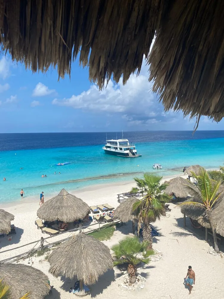 Wit strand met palapa's en een boot op Klein Curaçao